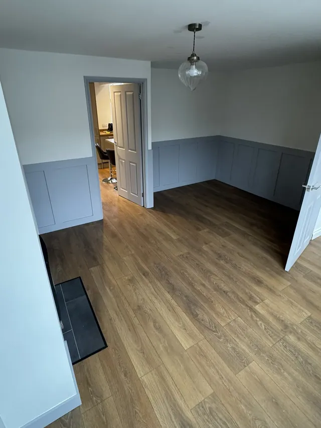 Living room with decorative wall panelling opening towards the kitchen