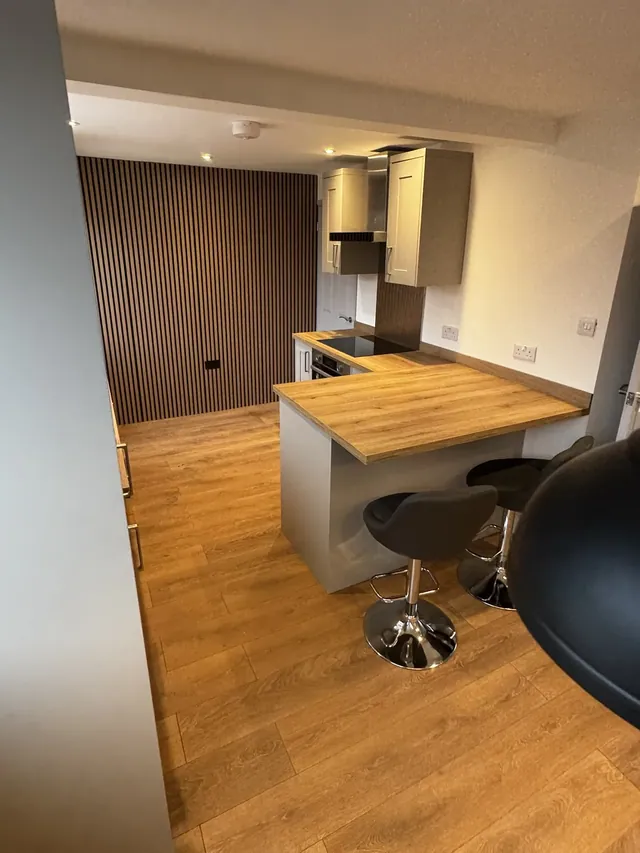 Fitted kitchen with breakfast bar, stools and a slatted feature wall