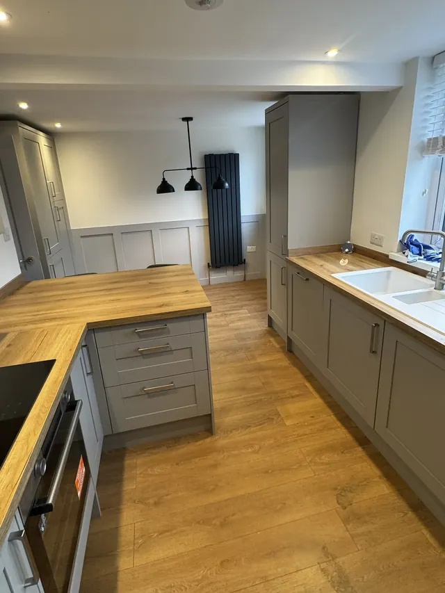 Finished kitchen with grey cabinets and wood-tone worktops