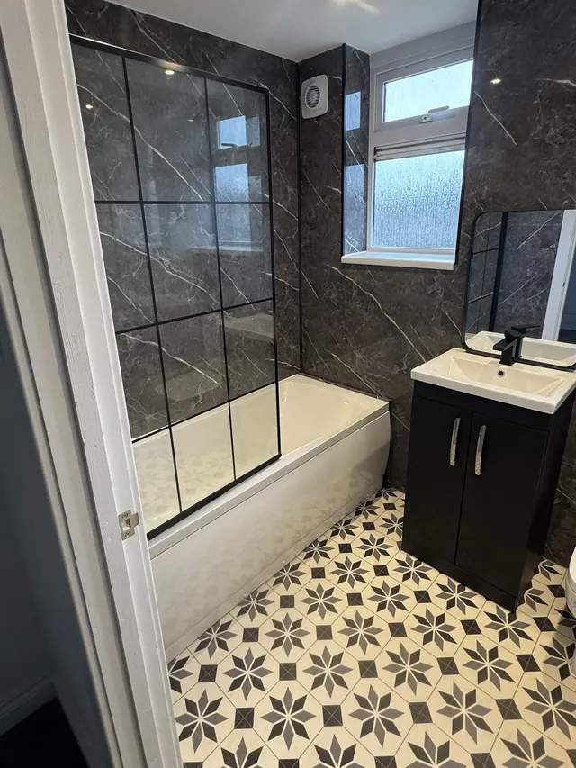 Finished bathroom with bath, black-framed shower screen and patterned floor