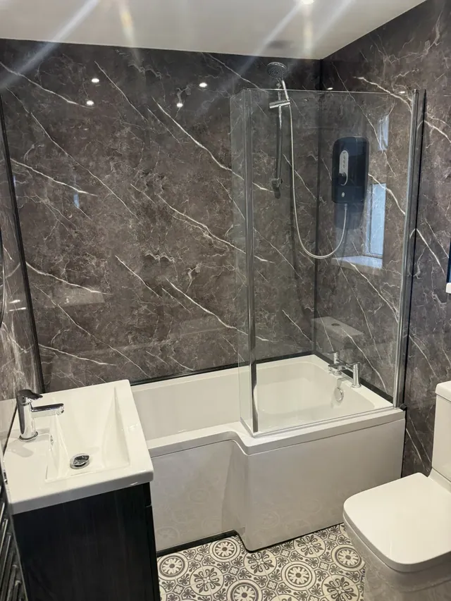 Fitted bathroom with bath, shower screen and marble-effect wall panels