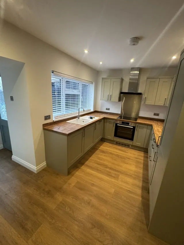 Fitted kitchen with grey units, wood-effect worktops and new floor finish