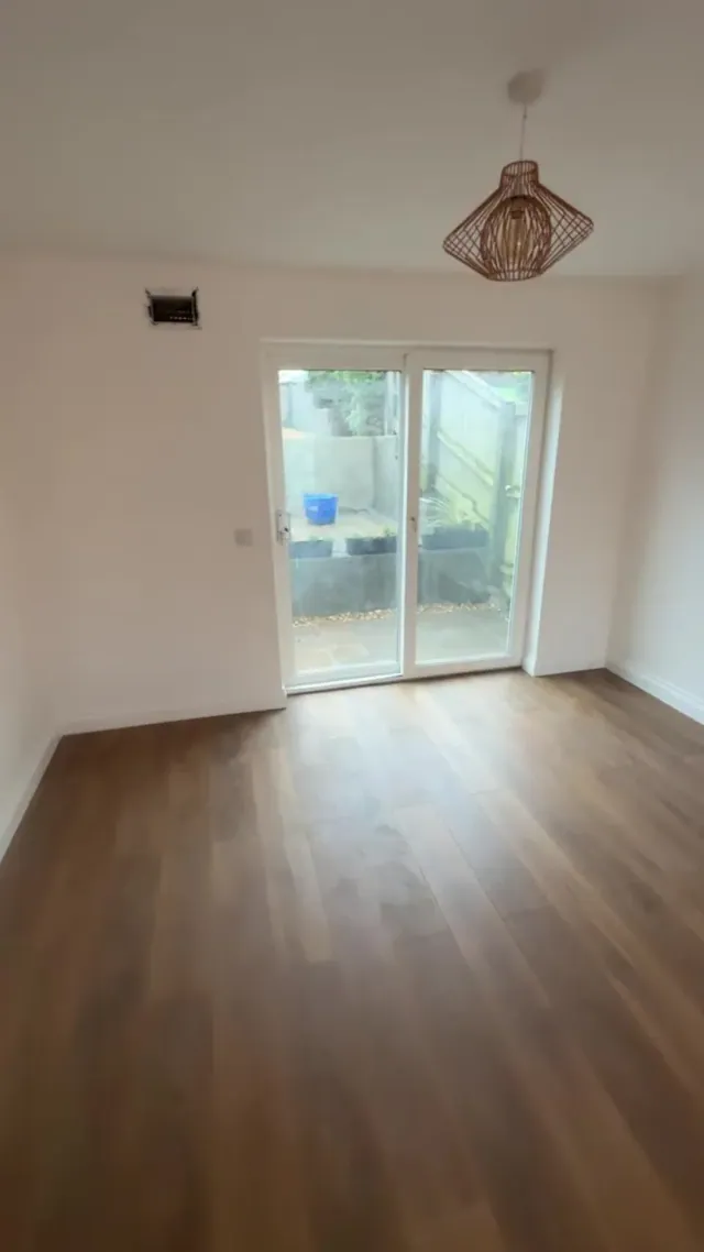 Later view of the living area, floor finish and doors to the garden