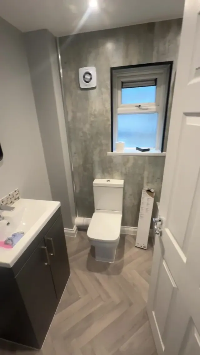 Refitted bathroom with vanity unit, toilet, wall panels and patterned floor finish
