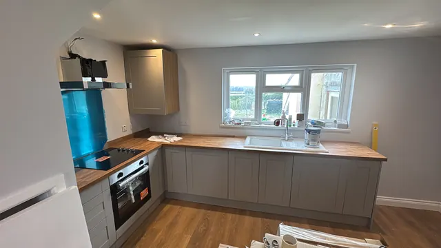 Fitted grey kitchen with wood-tone worktops at the finishing stage