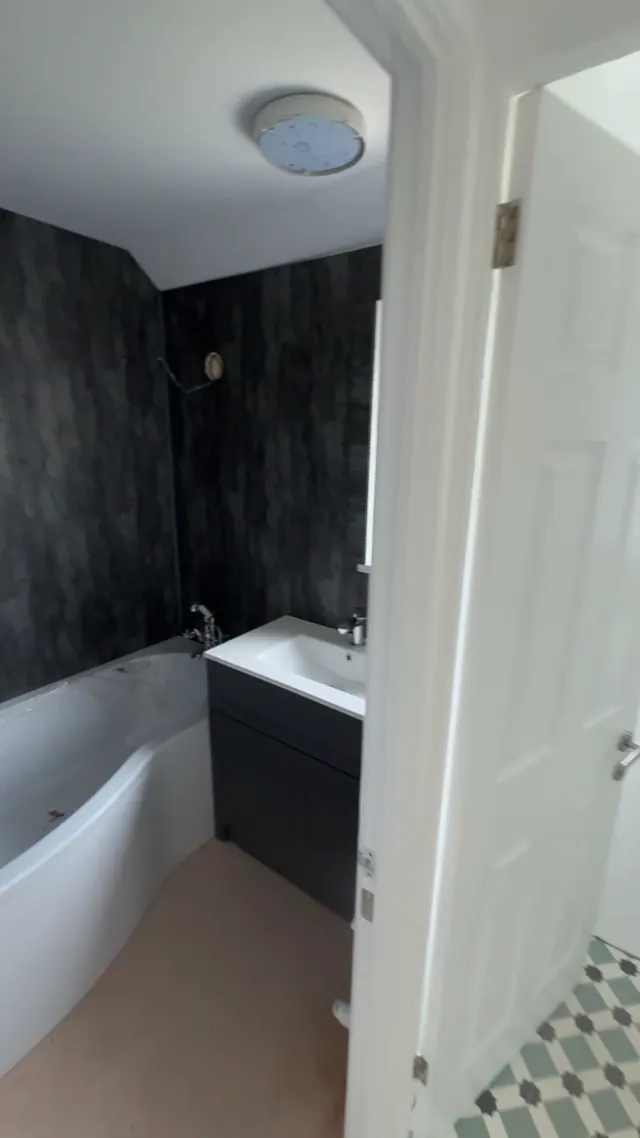Later view of the bath and dark bathroom wall panels