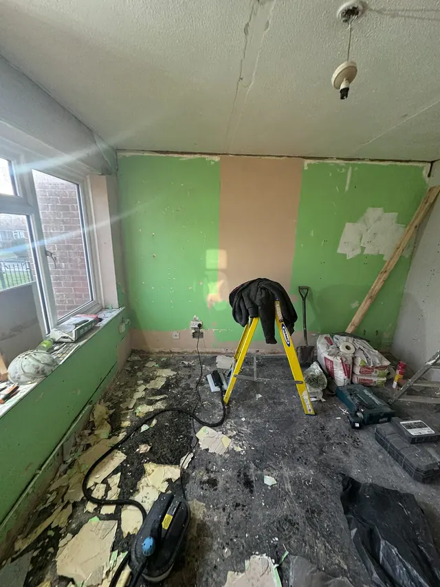 Living room with original green walls during early preparation