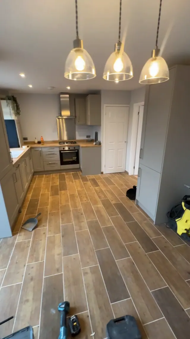 Later view of the fitted kitchen with pendant lighting and coordinated floor finish